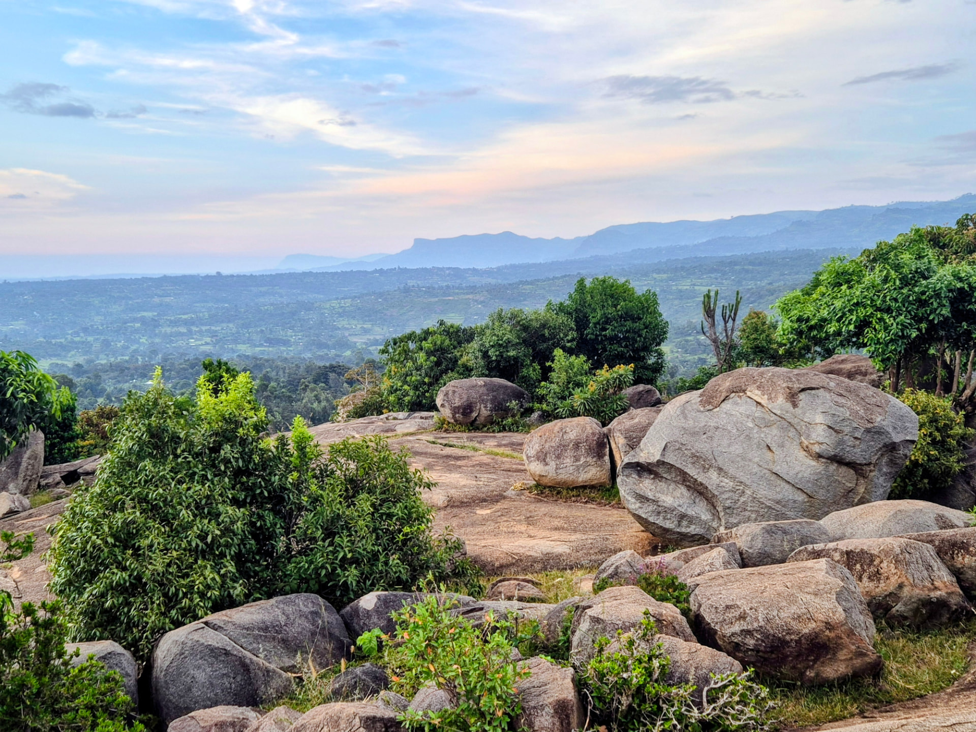 Rocky outcrops above forested hills and distant mountains at dusk