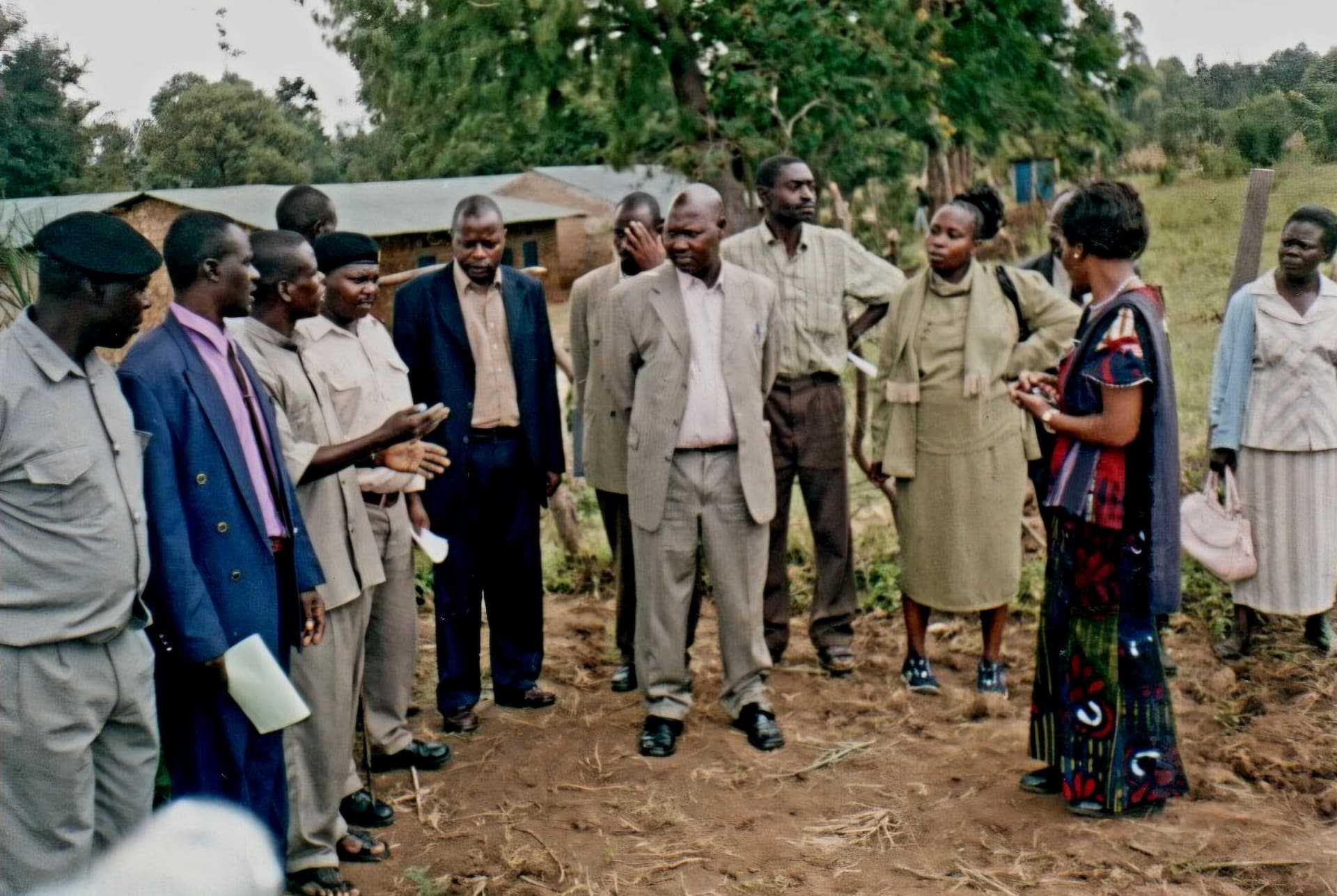 A group of officials and community members standing together on a prepared planting site