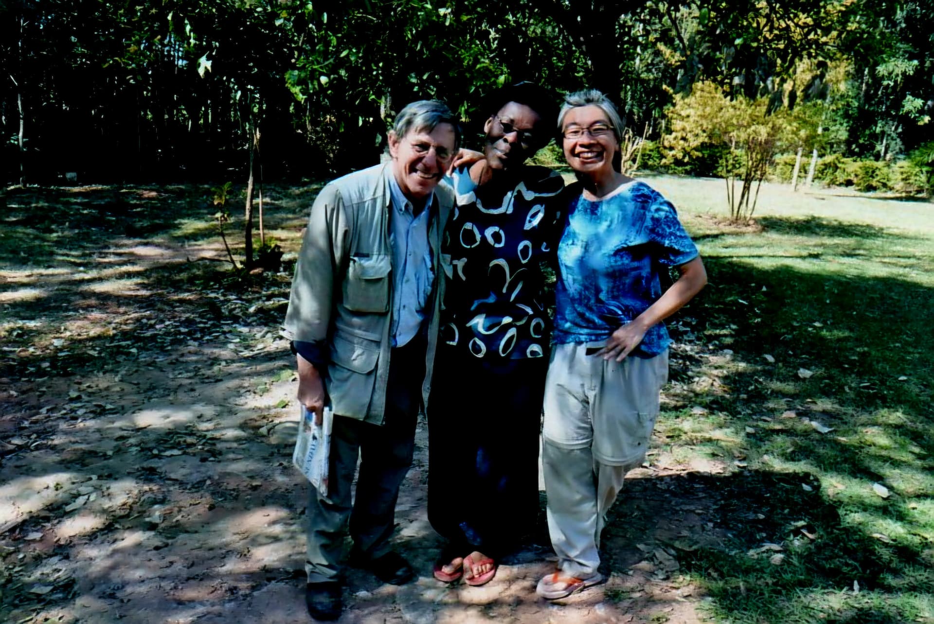 Three people standing arm in arm among trees at the resource centre