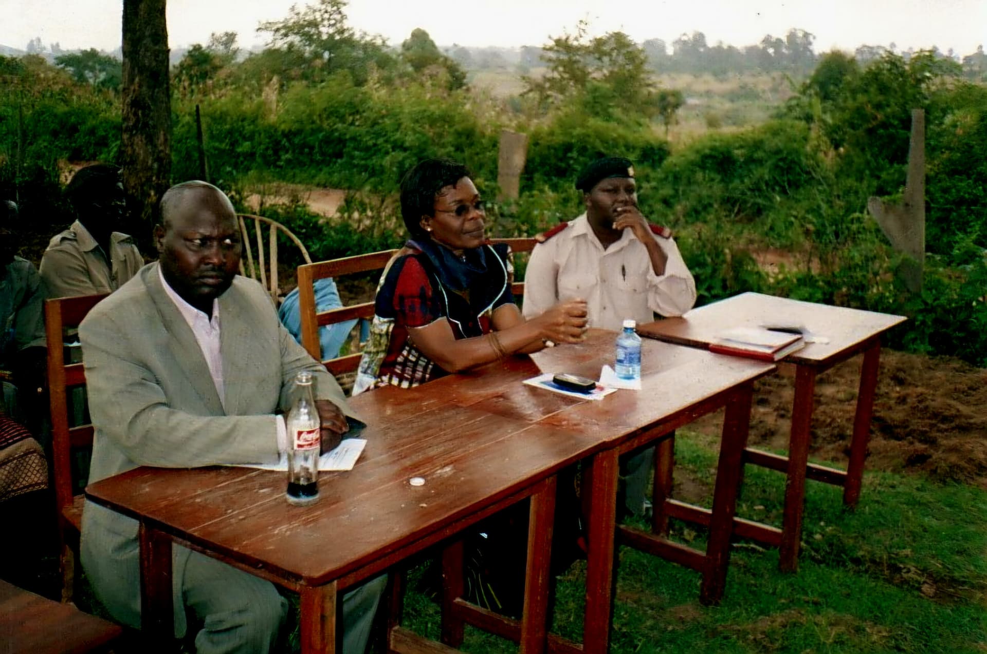 Three officials seated at the head table outdoors during the proceedings