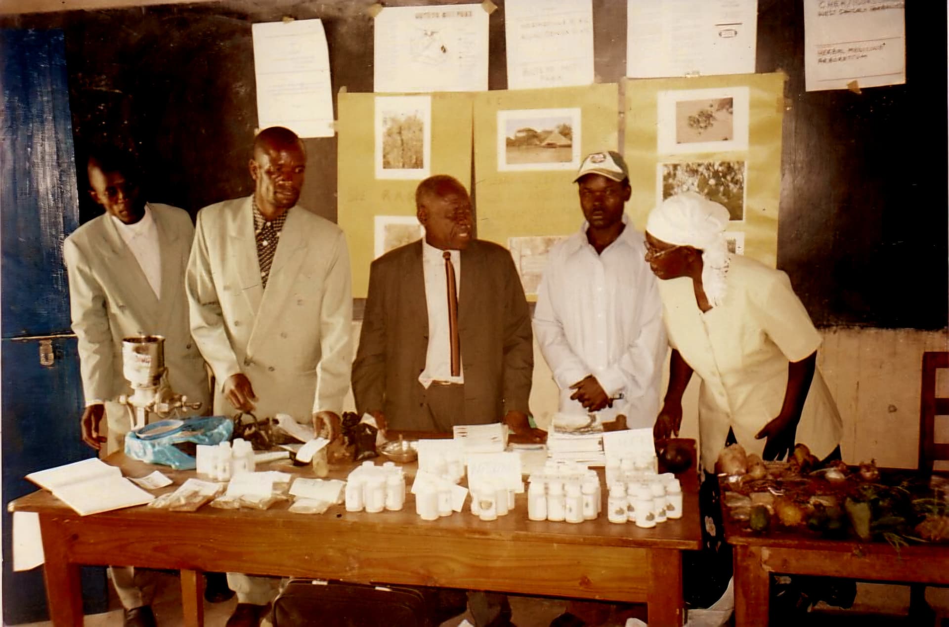 People standing behind an exhibition table of seed samples, bottles and produce