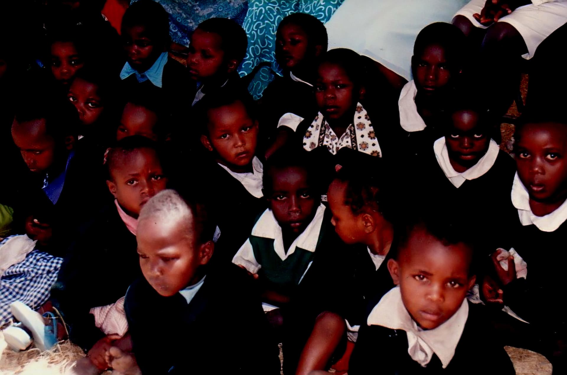A close group of young pupils in school uniform looking towards the camera